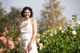 Christine Dion souriante, la main posée sur le cœur, au milieu d'un champ de dahlias en fleurs.